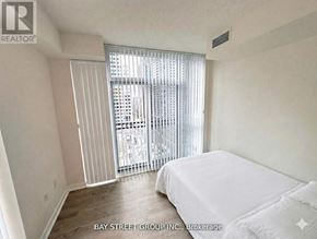 Toronto (Waterfront Communities) condo for rent - A bedroom with a large bed and a sliding glass door leading to a balcony.