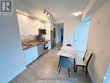 Toronto (Waterfront Communities) condo for rent - A kitchen with white cabinets and a counter with a chair and a person sitting at it.