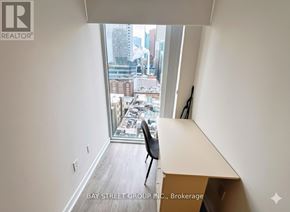 Toronto (Waterfront Communities) condo for rent - A room with a desk and a chair with a window that has a view of the city.