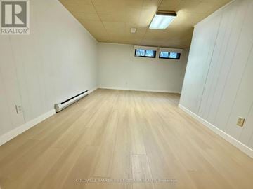 Ottawa apartment for rent - A spacious room with wooden flooring and white walls.
