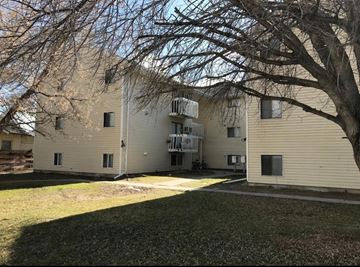 Pocatello apartment for rent - A tree is in front of a tan building.
