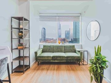 Edmonton apartment for rent - A living room with a green couch and a view of the city.