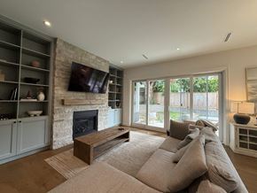 Surrey apartment for rent - A modern living room with a stone fireplace and a large flat screen TV mounted above it.