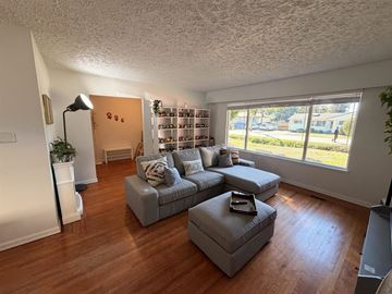 Surrey apartment for rent - A living room with a grey couch and ottoman, a lamp, and a bookshelf.