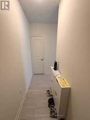 Toronto (Mimico) condo for rent - A hallway with a white door and a white cabinet with papers on it.