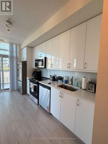 Toronto (Mimico) condo for rent - A kitchen with white cabinets and a stainless steel refrigerator.