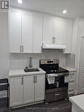 Toronto (Woburn) apartment for rent - A kitchen with white cabinets and a black stove top oven.