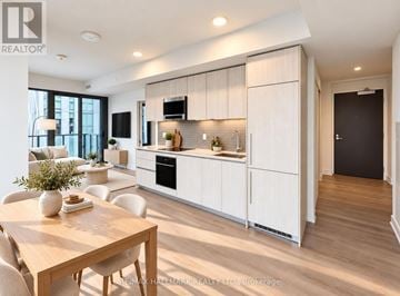 Toronto (Annex) condo for rent - A modern kitchen with white cabinets and a wooden table.