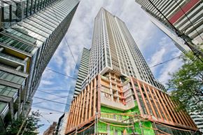 Toronto (Waterfront Communities) condo for rent - A tall building under construction with a green safety net around it.