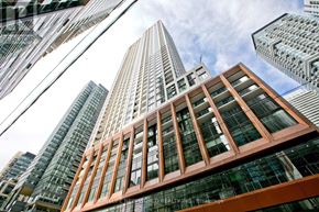 Toronto (Waterfront Communities) condo for rent - A tall building with a glass facade stands in front of other skyscrapers.