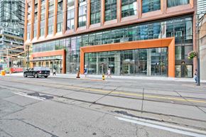 Toronto (Waterfront Communities) condo for rent - A street view of a building with a large glass window and a black car parked in front.