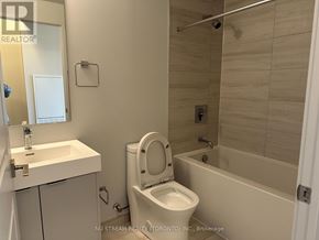 Vaughan (Concord) condo for rent - A white toilet is in a small bathroom with a white sink and a white bathtub.