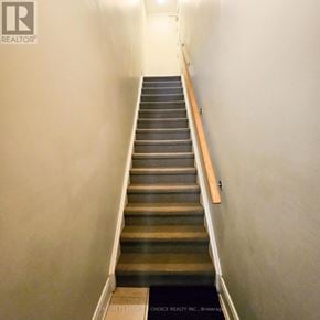 Oakville (Wm Westmount) townhouse for rent - A staircase with a wooden handrail and a black mat at the bottom.