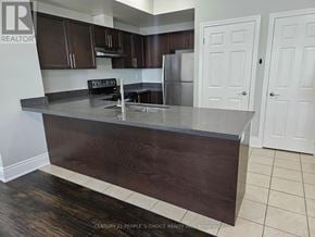 Oakville (Wm Westmount) townhouse for rent - A kitchen with dark wood cabinets and a stainless steel refrigerator.