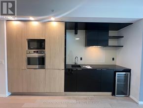 Toronto (Bay Street Corridor) condo for rent - A modern kitchen with wooden cabinets and black countertops.