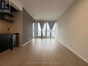 Toronto (Bay Street Corridor) condo for rent - A spacious room with a kitchen area and a large window with curtains.