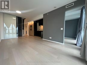 Toronto (Bay Street Corridor) condo for rent - A spacious room with a grey wall and a wooden floor.