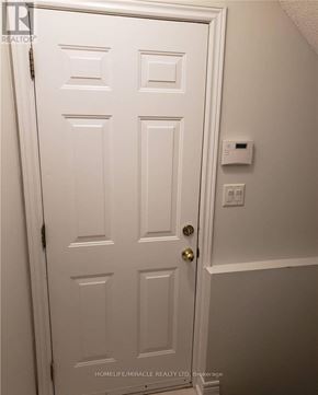Brampton (Snelgrove) apartment for rent - A white door with a gold handle and a light switch on the wall.