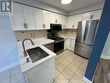 Mississauga (Lisgar) townhouse for rent - A kitchen with white cabinets and a stainless steel refrigerator.
