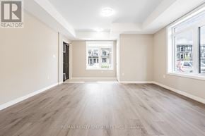Guelph (Kortright East) townhouse for rent - A spacious room with wooden flooring and a large window.