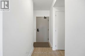 King (King City) condo for rent - A white hallway with a door and a brokerage sign.