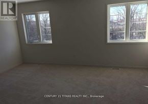 Oshawa (Windfields) apartment for rent - A room with a window showing a view of trees and a wall with a logo for Century 21 Titans Realty Inc., Brokerage.