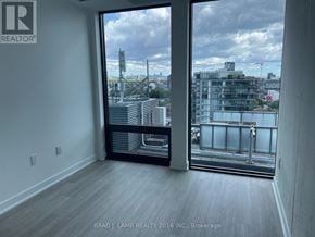 Toronto (Moss Park) condo for rent - A room with a large window overlooking a cityscape.