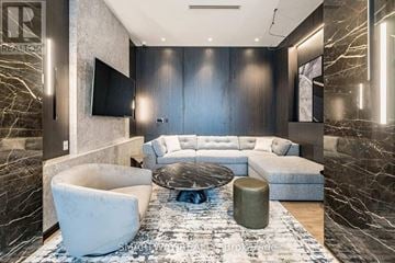 Toronto (Islington-City Centre West) condo for rent - A modern living room with a large couch and a TV mounted on the wall.