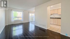 Mississauga (Churchill Meadows) townhouse for rent - A spacious room with wooden floors and white walls, featuring a large window with a view of greenery outside.