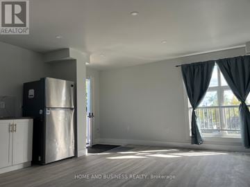 Thorold (Thorold Downtown) apartment for rent - A spacious kitchen with a refrigerator and a large window with curtains.