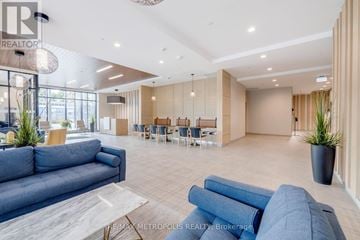 Kitchener condo for rent - A spacious living room with a blue sofa and a dining area in the background.