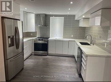 Clarington (Bowmanville) apartment for rent - A modern kitchen with a refrigerator, oven, and sink.