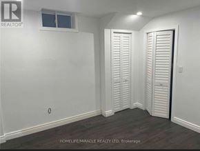 Clarington (Bowmanville) apartment for rent - A room with white walls and wooden flooring, with a window and two doors.