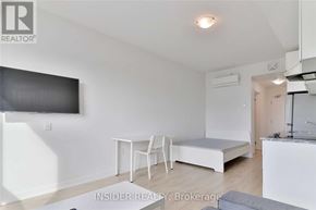 Oshawa (Samac) condo for rent - A white room with a bed, a table and a television.