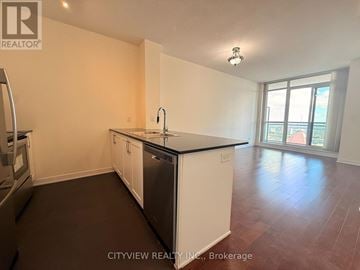 Mississauga (City Centre) condo for rent - A kitchen with white cabinets and black countertops.