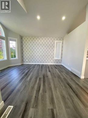 Calgary apartment for rent - A room with wooden flooring and a diamond patterned wallpaper.