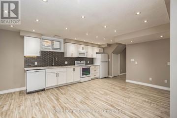 Guelph (Kortright East) apartment for rent - A kitchen with white cabinets and a brick backsplash.