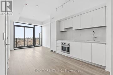 Toronto (Thorncliffe Park) condo for rent - A modern kitchen with white cabinets and a large window overlooking a cityscape.