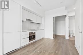 Toronto (Thorncliffe Park) condo for rent - A white kitchen with a wooden floor and a white toilet in the hallway.