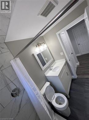 Kitchener apartment for rent - A bathroom with a toilet, sink, and mirror.