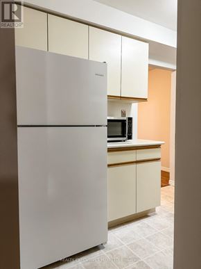 Orangeville multi-family for rent - A white refrigerator in a kitchen with a microwave on the counter.