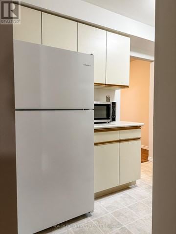 Orangeville multi-family for rent - A white refrigerator in a kitchen with a microwave on the counter.