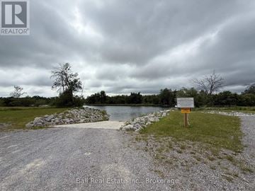 Otonabee-South Monaghan apartment for rent - A sign stands in a grassy area by a body of water under a cloudy sky.