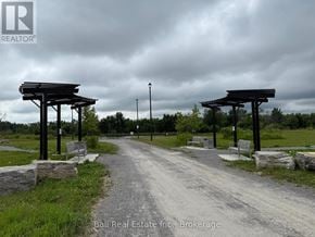 Otonabee-South Monaghan apartment for rent - A dirt road leads to a park with two wooden pergolas on either side.