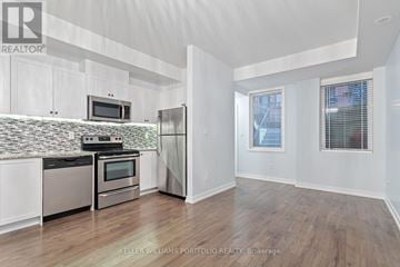 Toronto (Downsview-Roding-Cfb) townhouse for rent - A kitchen with white cabinets and a tiled backsplash.