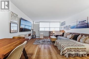 Oakville (Br Bronte) condo for rent - A living room with a wooden table and a couch with a striped blanket on it.
