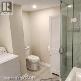 Hamilton apartment for rent - A white toilet sits next to a glass shower door in a bathroom.