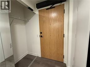 Brantford condo for rent - A wooden door in a room with white walls and a grey floor.