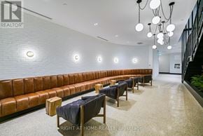Toronto (Junction Area) condo for rent - A long brown leather couch with a black cloth on it.