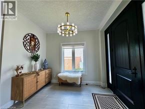 Kitchener apartment for rent - A room with a wooden cabinet, a chandelier, and a window with a view of a fence.